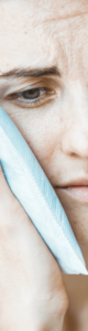 A woman experiencing missing teeth pain holding a cold compress to her cheek